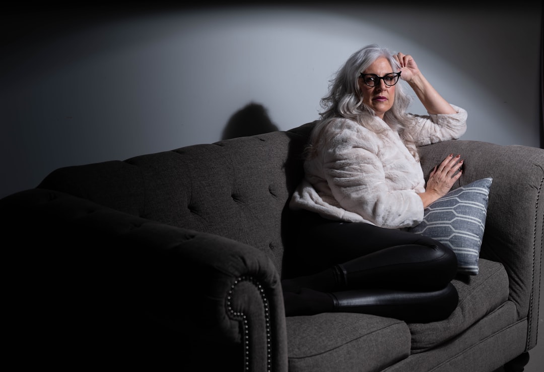 Femme seule sur un canapé illustrant les situations associées à la faim émotionnelle après 50 ans