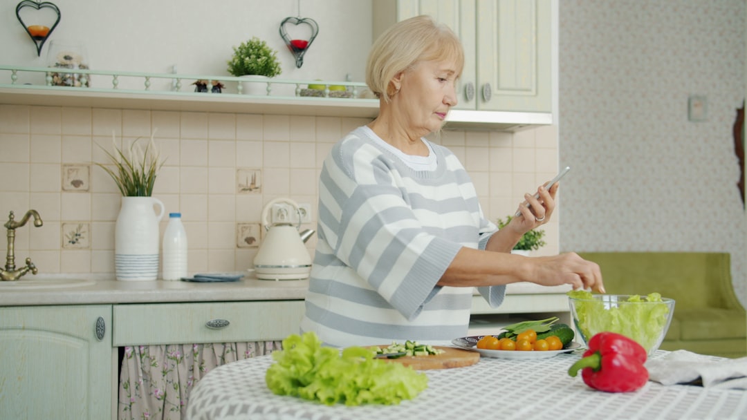 Femme préparant un repas tout en consultant son téléphone, illustration d’une alimentation équilibrée malgré un emploi du temps chargé